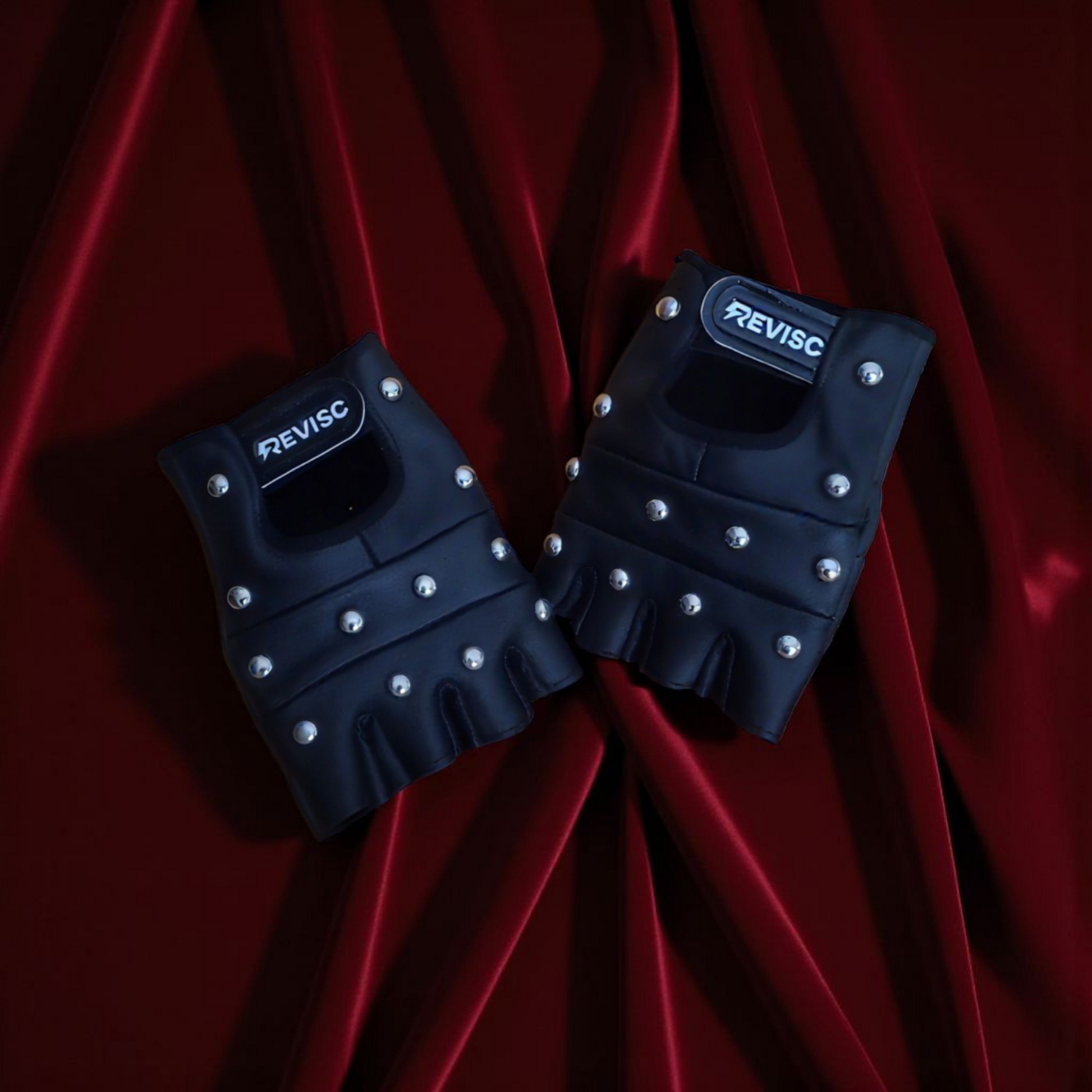 Black gloves with studded details on a red fabric background
